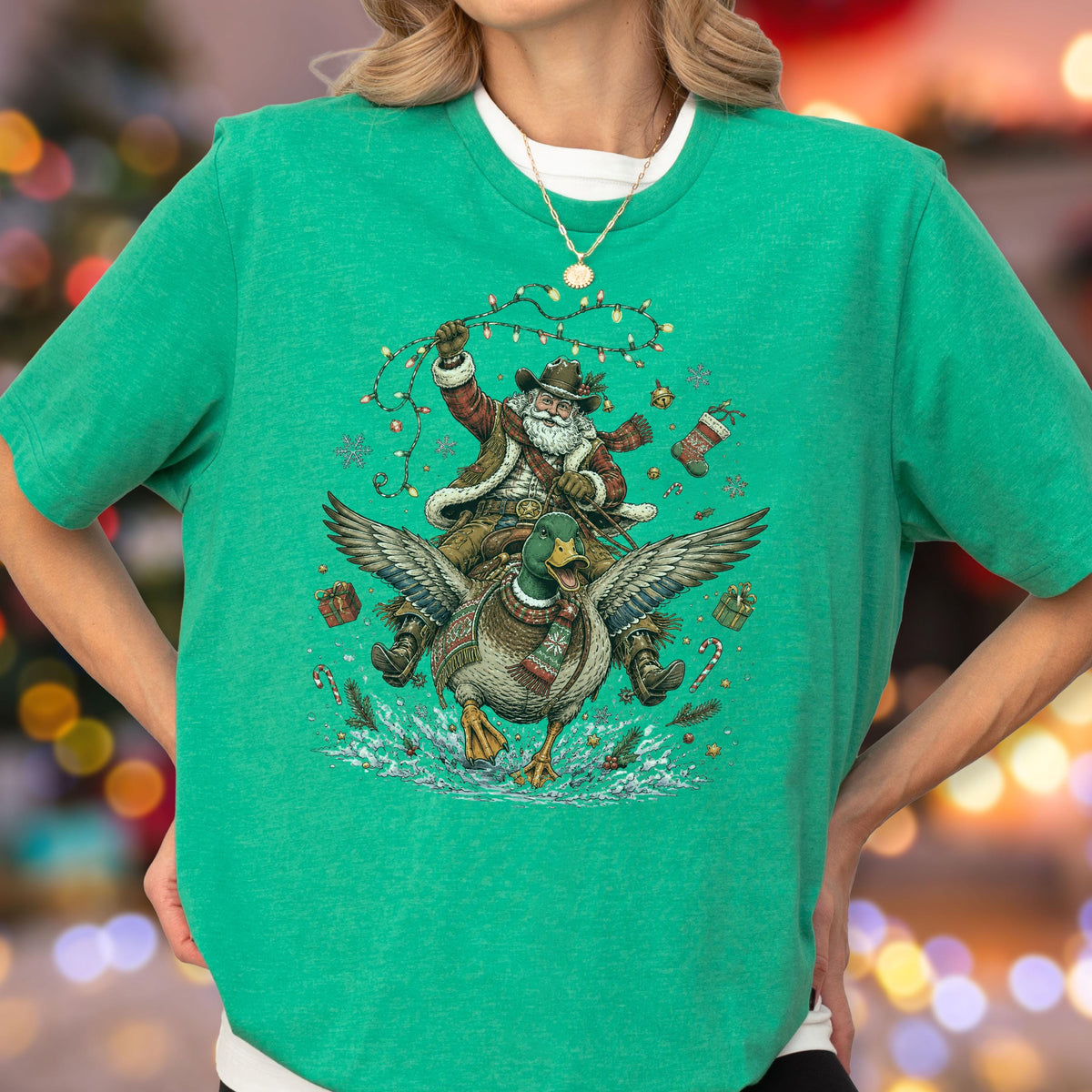 May include: A bright green short-sleeved t-shirt featuring a graphic illustration of Santa Claus wearing a cowboy hat and riding a flying mallard duck. The design includes festive elements like Christmas lights, snowflakes, and gifts.