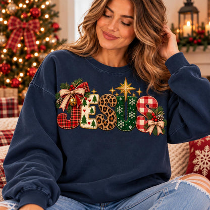 May include: A navy blue crewneck sweatshirt featuring the word JESUS in large, decorative letters. Each letter has a unique pattern including red plaid, white with green trees, leopard print, green with snowflakes, and red and white gingham.