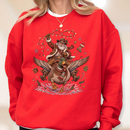 May include: A bright red crewneck sweatshirt featuring a graphic print of a cowboy Santa Claus riding a flying mallard duck. The design includes festive elements like string lights, a Christmas stocking, wrapped gifts, and candy canes.
