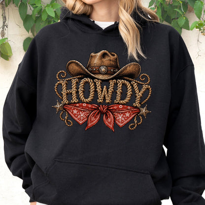 May include: A black hooded sweatshirt featuring a graphic print of a brown cowboy hat above the word HOWDY written in a rope-like font. Below the text is a red bandana with a white floral pattern, flanked by two small metallic-colored stars.
