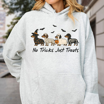May include: A light gray hooded sweatshirt featuring a graphic of four dachshunds in Halloween costumes, including a witch, a mummy, a ghost holding a pumpkin bucket, and a skeleton. The text "No Tricks Just Treats" is printed below the dogs.