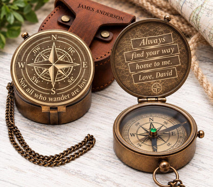 Personalized brass pocket compass with an engraved compass rose on the lid, a custom message inside, an antique-style chain and a brown leather case on cream fabric.