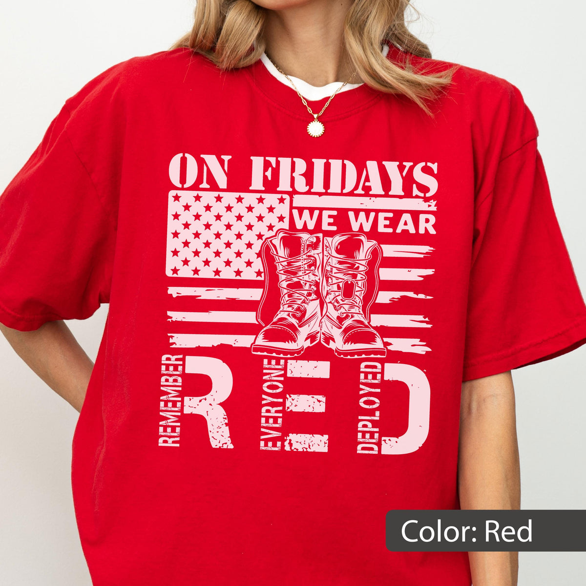 May include: A bright red short-sleeved t-shirt featuring a white graphic print of a stylized American flag, a pair of military boots, and the text ON FRIDAYS WE WEAR RED REMEMBER EVERYONE DEPLOYED. The design is centered on the front of the shirt.