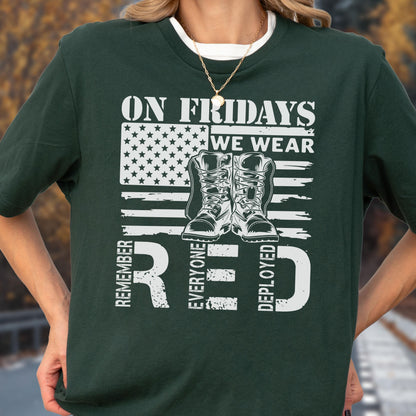 May include: A dark green short-sleeve t-shirt featuring a white graphic of an American flag and a pair of military boots. The text reads ON FRIDAYS WE WEAR RED, with the word RED also standing for REMEMBER EVERYONE DEPLOYED.