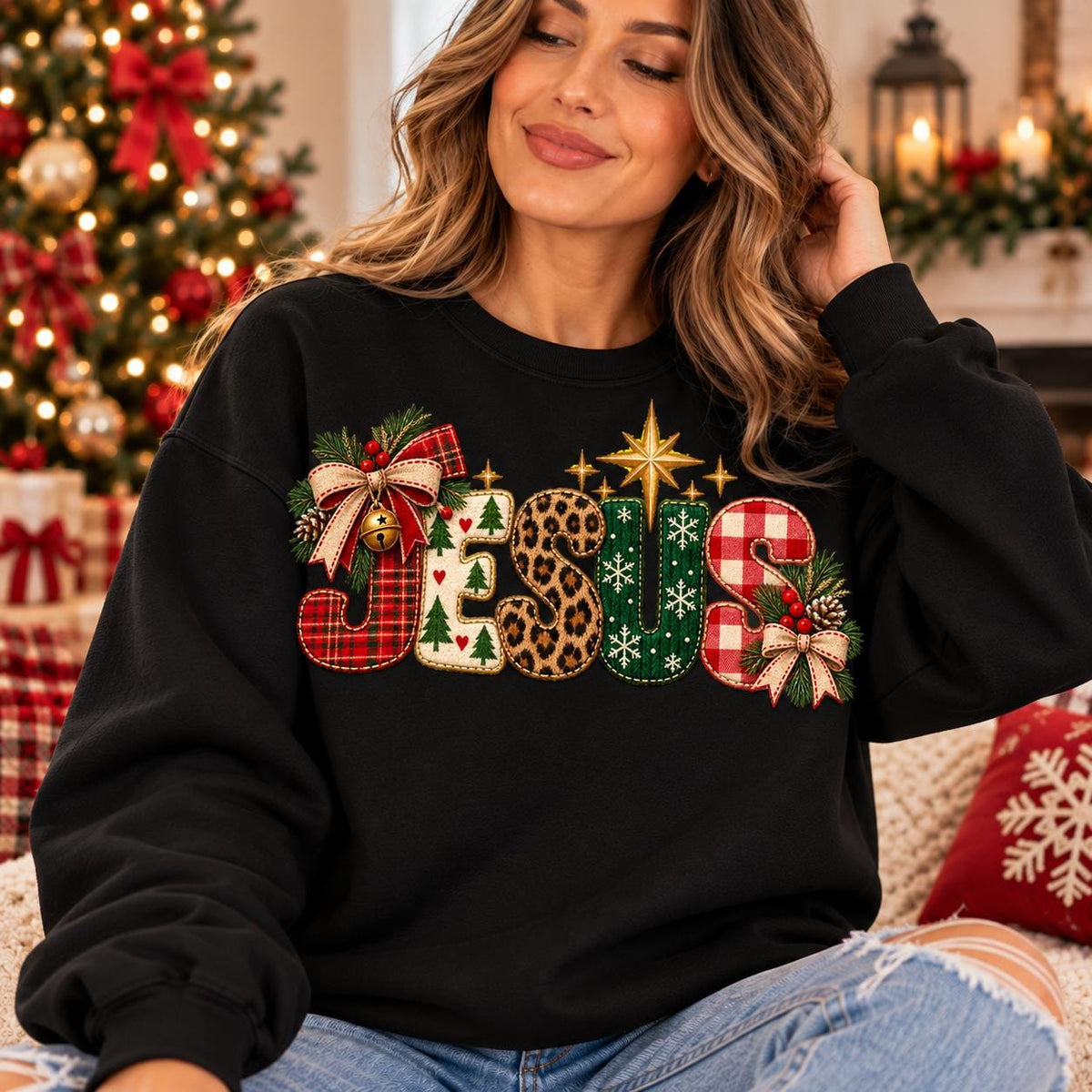 May include: A black long-sleeve sweatshirt featuring the word JESUS in large, decorative letters. Each letter has a unique pattern including red plaid, white with green trees, leopard print, green with white snowflakes, and red gingham with bows.