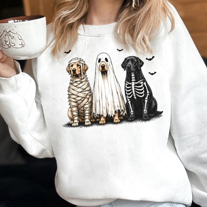 May include: A white crewneck sweatshirt featuring a graphic of three dogs in Halloween costumes: one wrapped as a mummy, one wearing a ghost sheet, and one with a skeleton print. Small black bats are scattered above the dogs.
